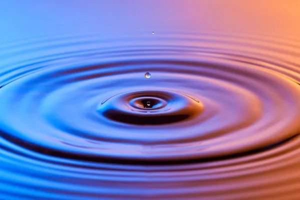 Goutte d'eau de près avec des ondulations concentriques bleu coloré et un — Photo