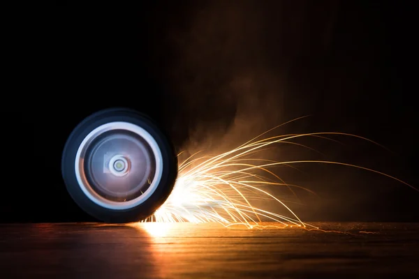 Toy wheel spinning on black background with sparks flying — Stock Photo, Image