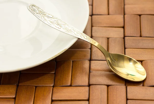 Plate and spoon on wooden background — Stock Photo, Image