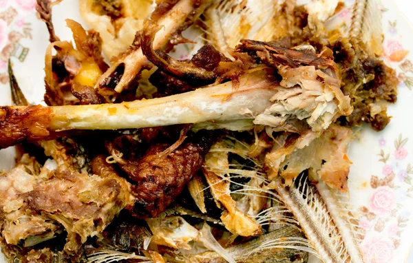 Residuos de alimentos, huesos de pescado y pollo en un plato — Foto de Stock