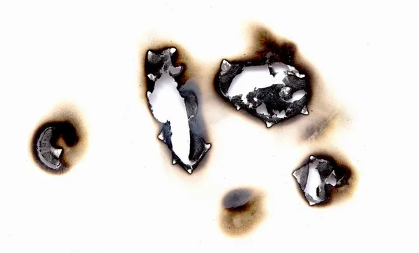 Verbrande gaten in een vel papier — Stockfoto