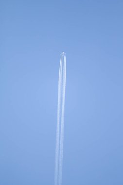 Mavi gökyüzü ve gökyüzünde yükselen uçak izleri.