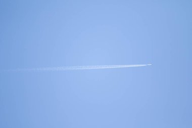 Mavi gökyüzü ve gökyüzünde yükselen uçak izleri.