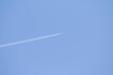 Mavi gökyüzü ve gökyüzünde yükselen uçak izleri.