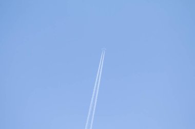 Mavi gökyüzü ve gökyüzünde yükselen uçak izleri.