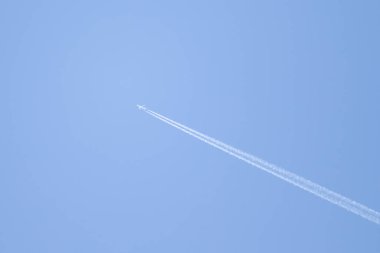 Mavi gökyüzü ve gökyüzünde yükselen uçak izleri.