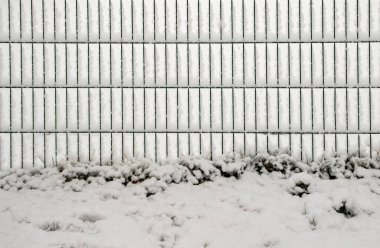 Karlı bir parkta kışın dekoratif metal çitler..