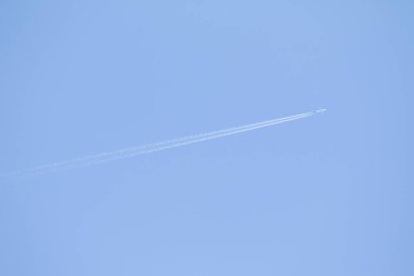 Mavi gökyüzü ve gökyüzünde yükselen uçak izleri.
