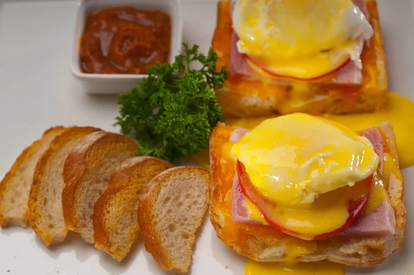 Eggs benedict on bread with tomato and ham — Stock Photo, Image