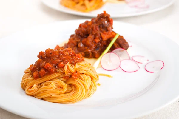 Pasta with pork ribbs sauce on polenta bed — Stock Photo, Image