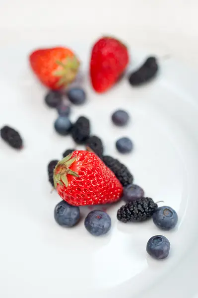 Berries on white plate — Stockfoto