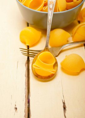 Çiğ İtalyan salyangoz lumaconi makarnası mavi bir kâse üzerinde rustik masa makrosu üzerinde