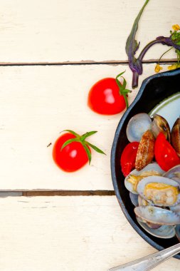 Demir tavada pişirilmiş taze midyeler sade ahşap masa üzerinde. 