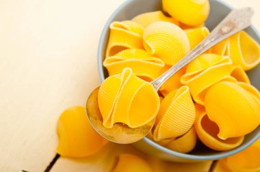 Çiğ İtalyan salyangoz lumaconi makarnası mavi bir kâse üzerinde rustik masa makrosu üzerinde