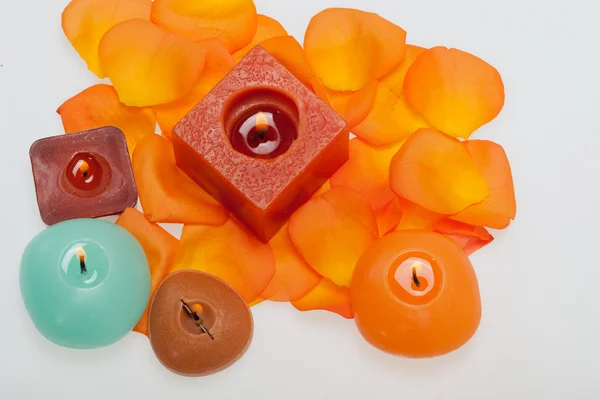 Spilt petals of the orange-rose around the aromatic candle — Stock Photo, Image