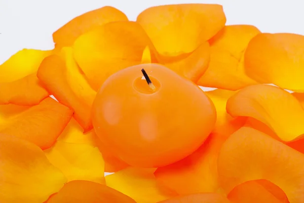 Spilt petals of the orange-rose around the aromatic candle — Stock Photo, Image