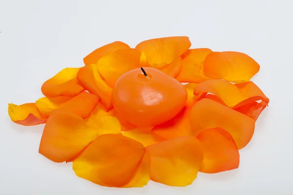 Verschüttete Blütenblätter der Orangenrose um die aromatische Kerze — Stockfoto