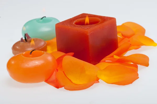 Spilt petals of the orange-rose around the aromatic candle — Stock Photo, Image