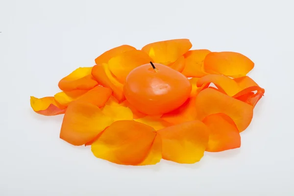 Spilt petals of the orange-rose around the aromatic candle — Stock Photo, Image