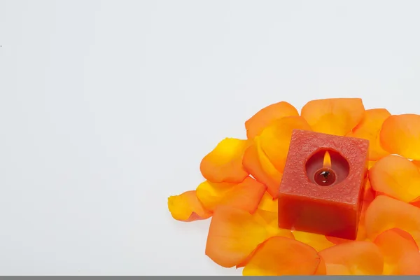 Spilt petals of the orange-rose around the aromatic candle — Stock Photo, Image