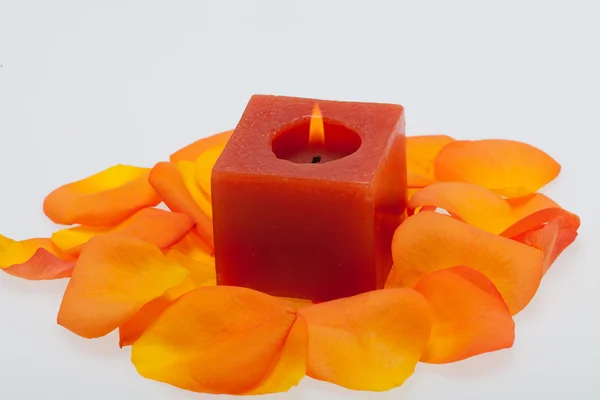 Spilt petals of the orange-rose around the aromatic candle — Stock Photo, Image