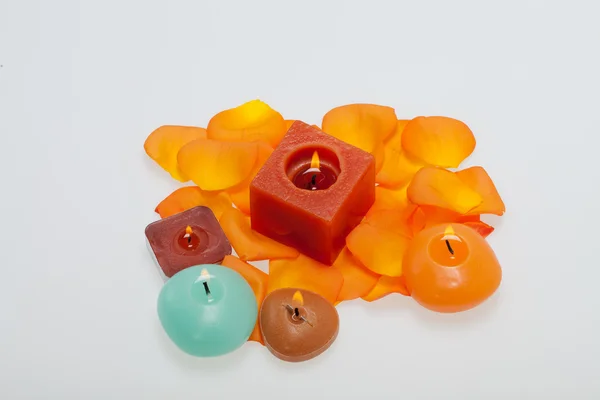 Spilt petals of the orange-rose around the aromatic candle — Stock Photo, Image