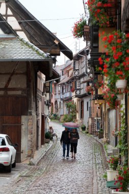Fransa 'nın Alsace kentindeki ünlü şarap rotası boyunca Eguisheim köyünde yarı ağaçlı ortaçağ evleri olan sokak.