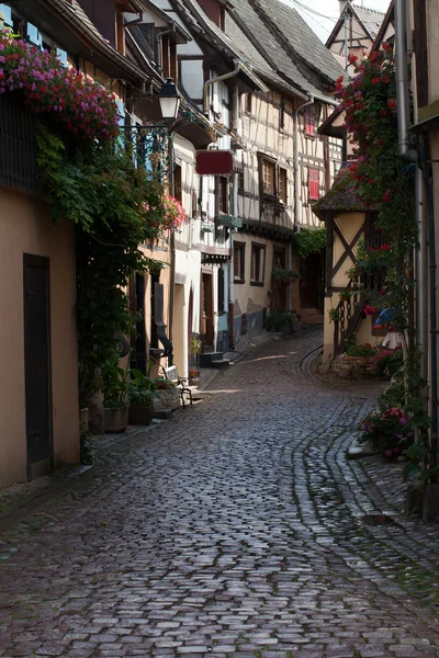 Strada con case medievali a graticcio nel villaggio di Eguisheim lungo la famosa strada del vino in Alsazia, Francia — Foto Stock