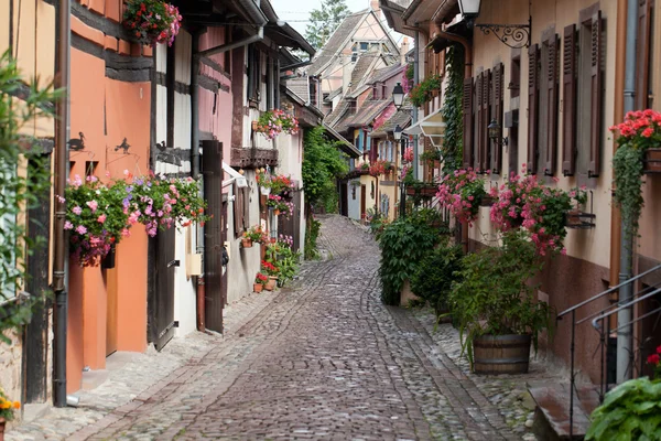 Rua com casas medievais de meia-madeira na aldeia de Eguisheim ao longo da famosa rota do vinho na Alsácia, França — Fotografia de Stock