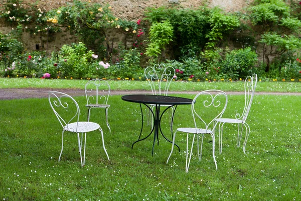 La table vide et quatre chaises blanches dans le jardin — Photo