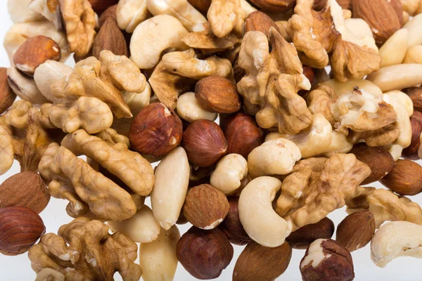 Pozadí smíšených ořechy - lískové oříšky, vlašské ořechy, Kešu ořechy, piniové oříšky — Stock fotografie
