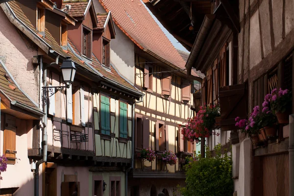 Strada con case medievali a graticcio nel villaggio di Eguisheim lungo la famosa strada del vino in Alsazia, Francia — Foto Stock