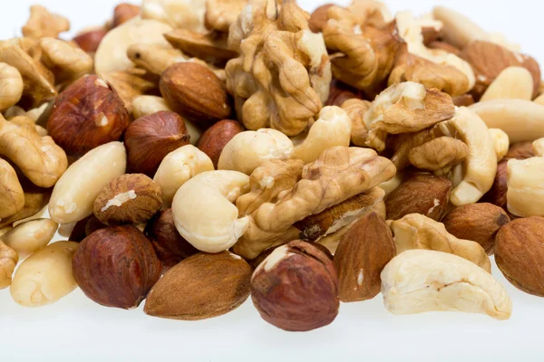 Gemengde noten - hazelnoten, walnoten, cashewnoten en pijnboompitten geïsoleerd op witte achtergrond — Stockfoto