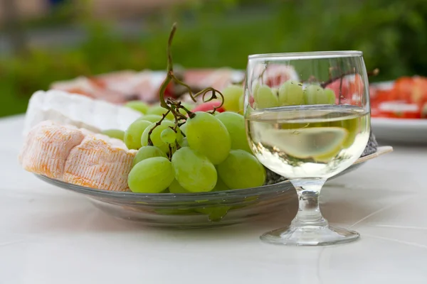 Verschiedene Käsesorten, Trauben und ein Glas Weißwein — Stockfoto