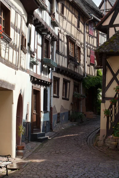 Rua com casas medievais de meia-madeira na aldeia de Eguisheim ao longo da famosa rota do vinho na Alsácia, França — Fotografia de Stock