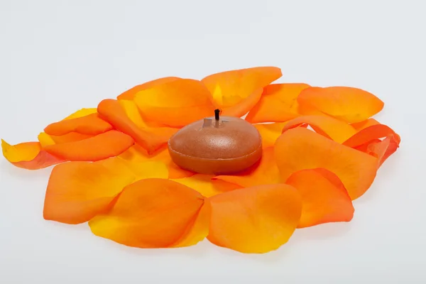 Verschüttete Blütenblätter der Orangenrose um die aromatische Kerze — Stockfoto