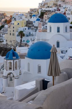 Yunan ortodoks Hıristiyan kiliseleri ve geleneksel beyaz boyalı Yunan mimarisinin mavi kubbelerine sahip Oia köyünün bakış açısından bak. Santorini, Yunanistan