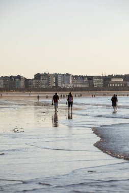 St. Malo, Fransa - 16 Eylül 2018: Saint Malo 'nun pitoresk plajında gün batımından önce insanların romantik yürüyüşü. Britanya, Fransa