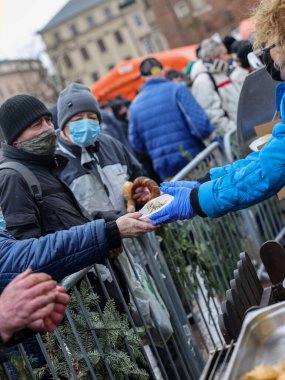 Krakow, Polonya - 19 Aralık 2021: Krakow 'daki ana meydandaki fakir ve evsizler için Noel arifesi. Covid salgınına rağmen Kosciuszko grubu Krakow 'daki açık havada en büyük arifeyi hazırlıyor.