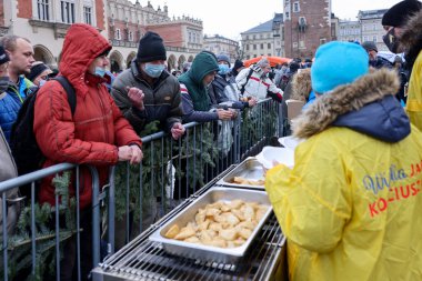Krakow, Polonya - 19 Aralık 2021: Krakow 'daki ana meydandaki fakir ve evsizler için Noel arifesi. Covid salgınına rağmen Kosciuszko grubu Krakow 'daki açık havada en büyük arifeyi hazırlıyor.
