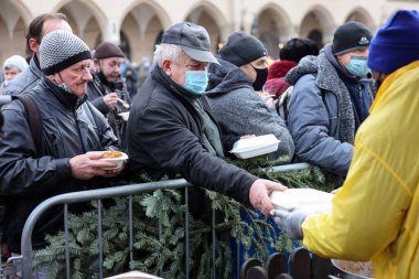 Krakow, Polonya - 19 Aralık 2021: Krakow 'daki ana meydandaki fakir ve evsizler için Noel arifesi. Covid salgınına rağmen Kosciuszko grubu Krakow 'daki açık havada en büyük arifeyi hazırlıyor.