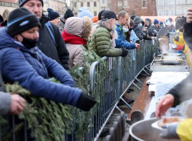 Krakow, Polonya - 19 Aralık 2021: Krakow 'daki ana meydandaki fakir ve evsizler için Noel arifesi. Covid salgınına rağmen Kosciuszko grubu Krakow 'daki açık havada en büyük arifeyi hazırlıyor.