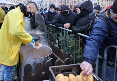 Krakow, Polonya - 19 Aralık 2021: Krakow 'daki ana meydandaki fakir ve evsizler için Noel arifesi. Covid salgınına rağmen Kosciuszko grubu Krakow 'daki açık havada en büyük arifeyi hazırlıyor.
