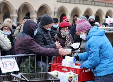 Krakow, Polonya - 19 Aralık 2021: Krakow 'daki ana meydandaki fakir ve evsizler için Noel arifesi. Covid salgınına rağmen Kosciuszko grubu Krakow 'daki açık havada en büyük arifeyi hazırlıyor.