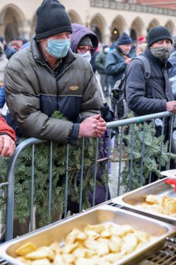 Krakow, Polonya - 19 Aralık 2021: Krakow 'daki ana meydandaki fakir ve evsizler için Noel arifesi. Covid salgınına rağmen Kosciuszko grubu Krakow 'daki açık havada en büyük arifeyi hazırlıyor.