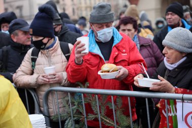 Krakow, Polonya - 19 Aralık 2021: Krakow 'daki ana meydandaki fakir ve evsizler için Noel arifesi. Covid salgınına rağmen Kosciuszko grubu Krakow 'daki açık havada en büyük arifeyi hazırlıyor.