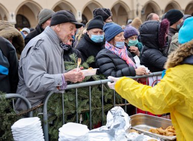 Krakow, Polonya - 19 Aralık 2021: Krakow 'daki ana meydandaki fakir ve evsizler için Noel arifesi. Covid salgınına rağmen Kosciuszko grubu Krakow 'daki açık havada en büyük arifeyi hazırlıyor.