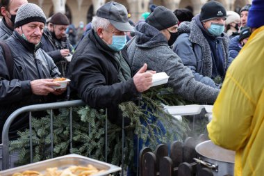 Krakow, Polonya - 19 Aralık 2021: Krakow 'daki ana meydandaki fakir ve evsizler için Noel arifesi. Covid salgınına rağmen Kosciuszko grubu Krakow 'daki açık havada en büyük arifeyi hazırlıyor.