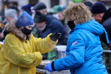 Krakow, Polonya - 19 Aralık 2021: Krakow 'daki ana meydandaki fakir ve evsizler için Noel arifesi. Covid salgınına rağmen Kosciuszko grubu Krakow 'daki açık havada en büyük arifeyi hazırlıyor.