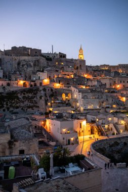 Matera, İtalya - 20 Eylül 2019: Matera, İtalya 'nın akşam manzarası, Sassi di Matera şehrinin tarihi bir bölgesi olan Sassi di Matera' daki kaldırım kafelerinin avlularını aydınlatan renkli ışıklarla. Basilicata. İtalya
